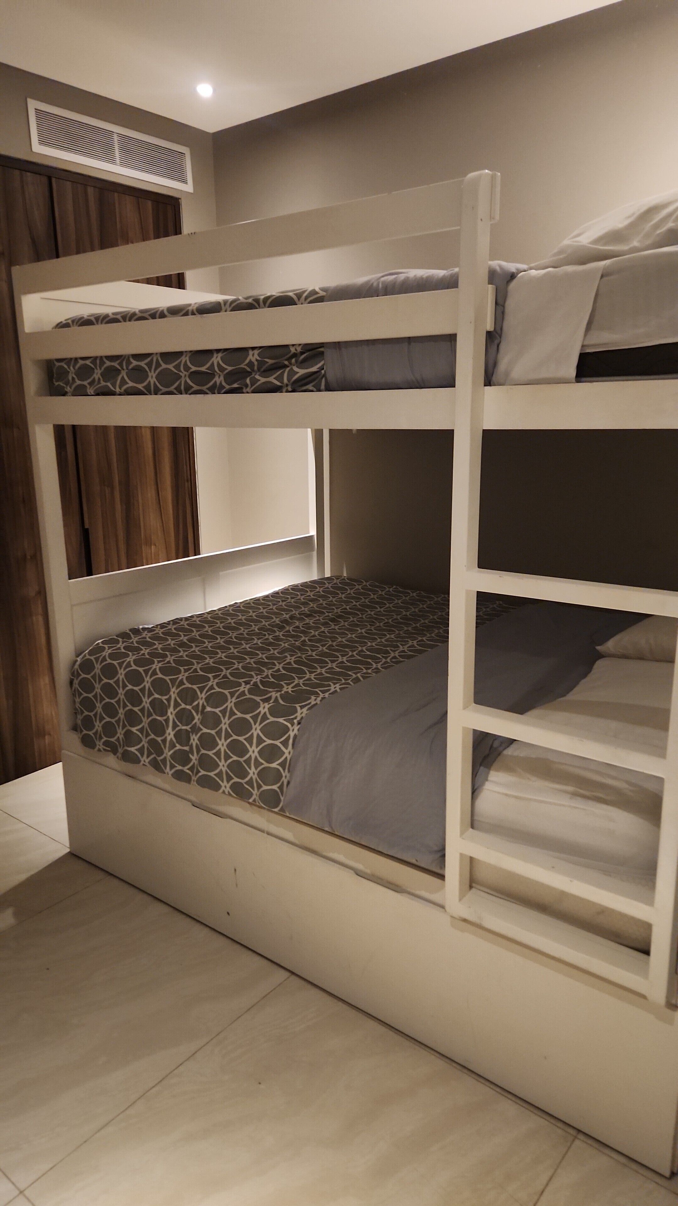 Un lit superposé avec un matelas à motifs, une échelle et une tête de lit.