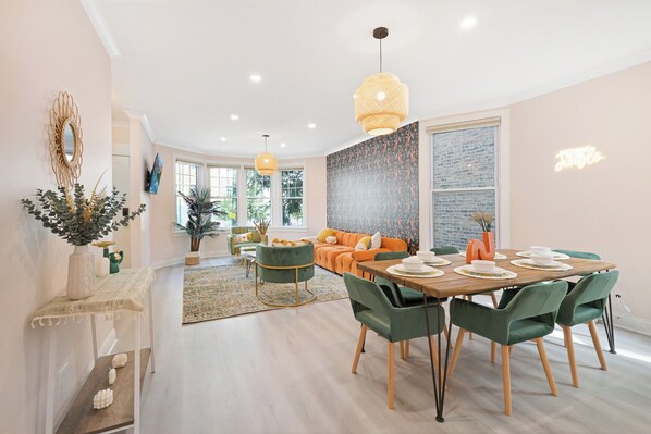 Un comedor moderno con una mesa de madera, sillas verdes y un ventanal grande.
