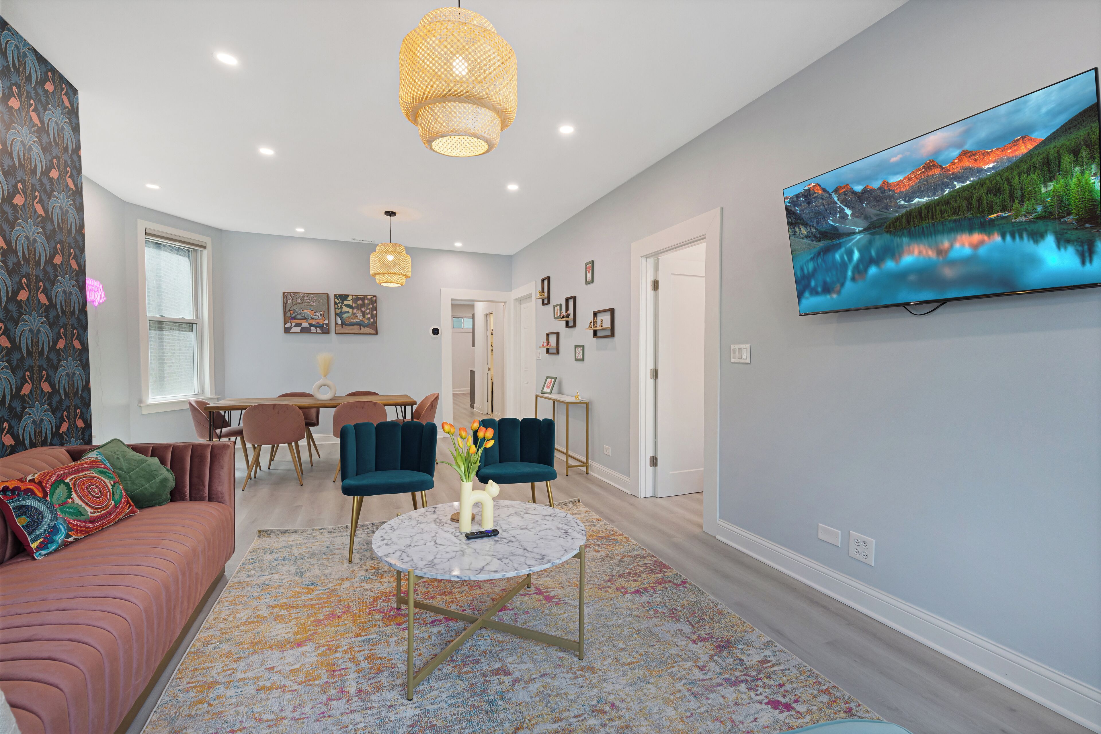 A modern living room with a sofa, chairs, a coffee table, and a painting on the wall.