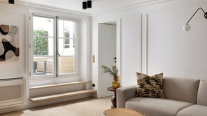 Un salon moderne avec un canapé, une table basse et une fenêtre donnant sur un paysage verdoyant.