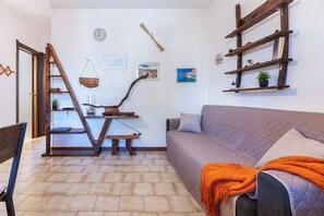 Un salon avec une échelle en bois, un canapé, un banc et une étagère murale agrémentée de plantes.
