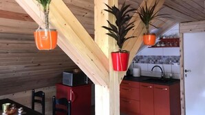 A kitchen with wooden beams, a red cabinet, and hanging plants in orange pots.