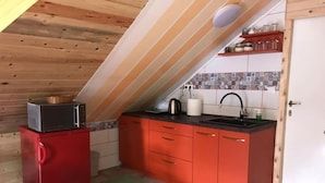 A compact kitchen with a microwave, sink, and red cabinets.