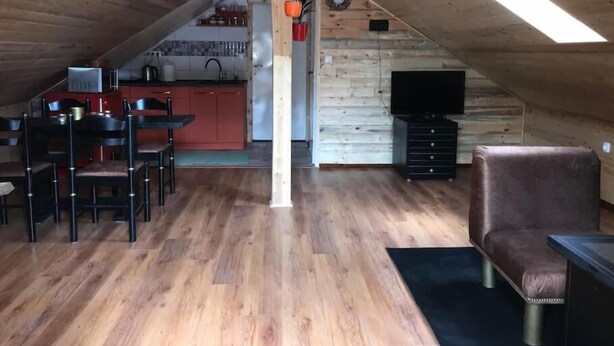 An attic room with a dining area, kitchen, and seating.