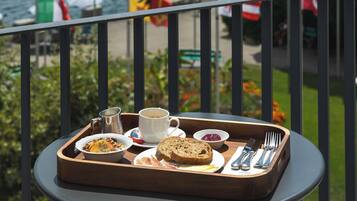A balcony table with breakfast items, flags, and a lake view.