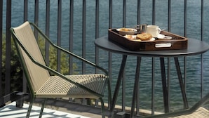 Un balcón con mesa y sillas, con vista a una masa de agua y montañas.