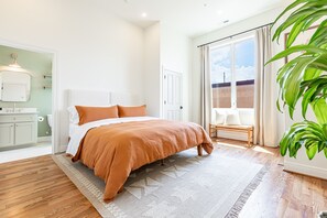 Relax in this serene bedroom with a large bed and a view of the outside through the window.