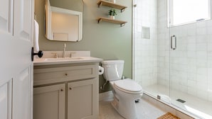 Un bagno con lavandino bianco, servizi igienici, uno specchio e una doccia.