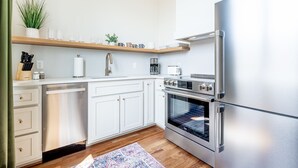 Una cucina moderna con mobili bianchi, un frigorifero in acciaio inossidabile e un forno a incasso.