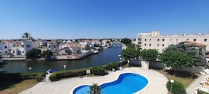 A swimming pool with a view of a river and buildings in the background. - Splendid apartment overlooking the canals and the swimming poo (Empuriabrava)