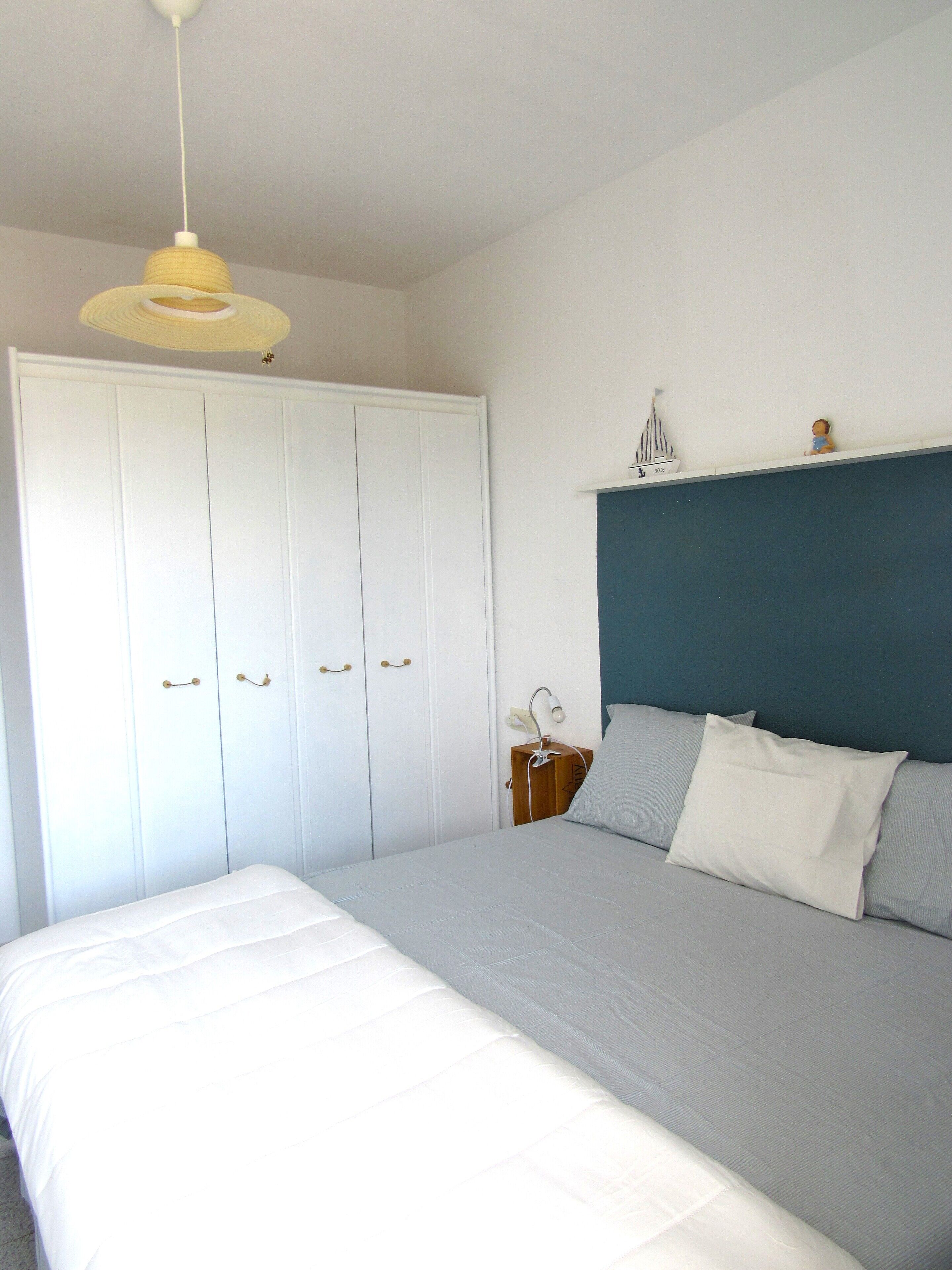 Un dormitorio con una cama, una mesita de noche, una lámpara y un armario.