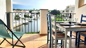 A balcony with a table set for two, overlooking a canal with boats.