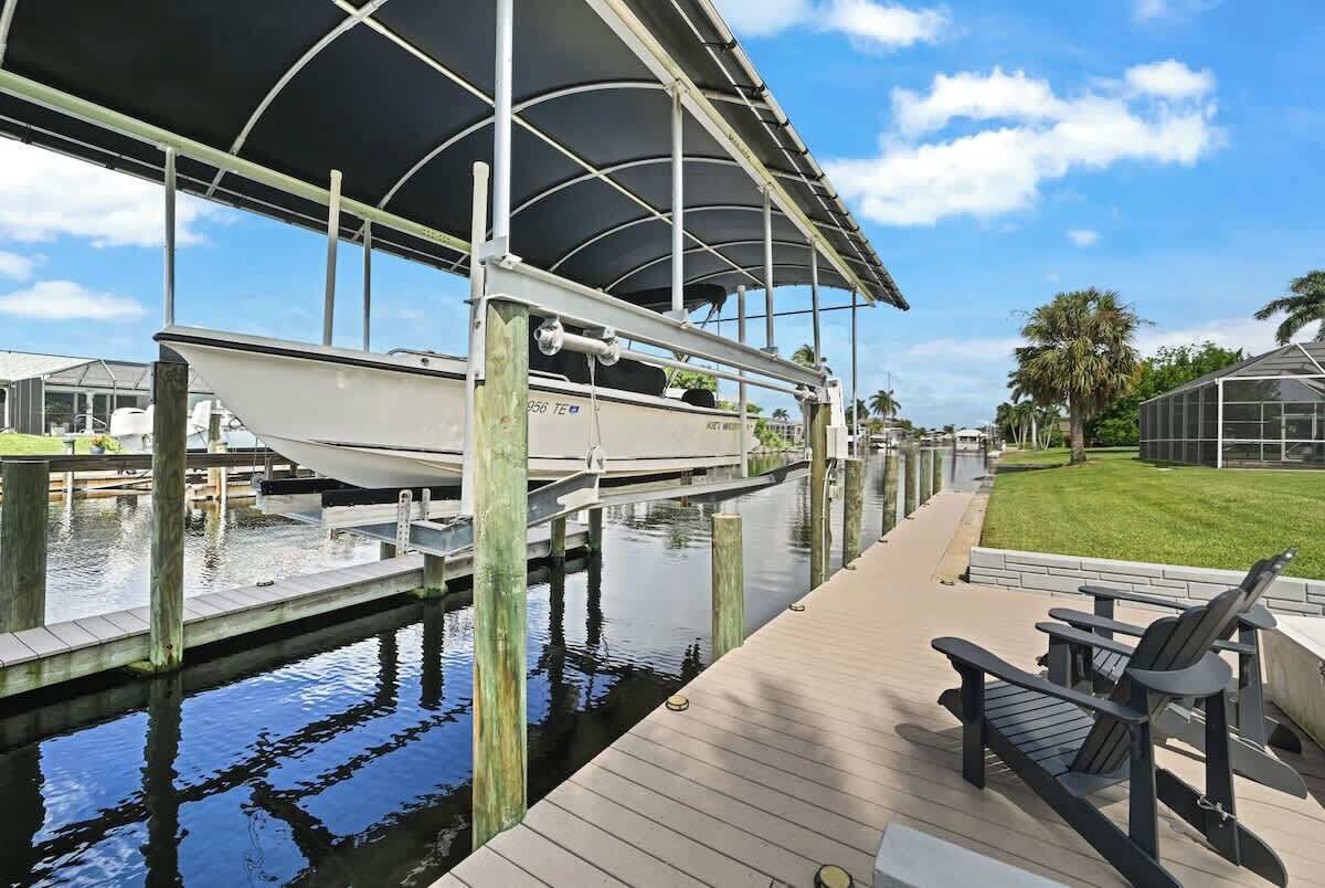 A boat docked under a covered area with a wooden deck and a chair.