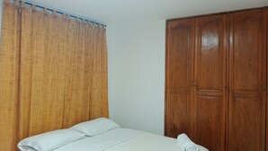 Un dormitorio con una cama, un armario de madera y una cortina.