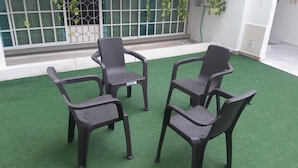 Cuatro sillas negras de plástico con superficie texturizada, dispuestas sobre una capa de césped artificial verde.