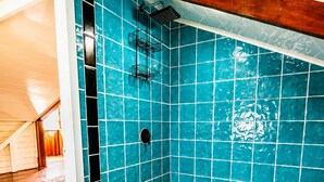 A bathroom with blue tiles, a shower, and a wooden floor.