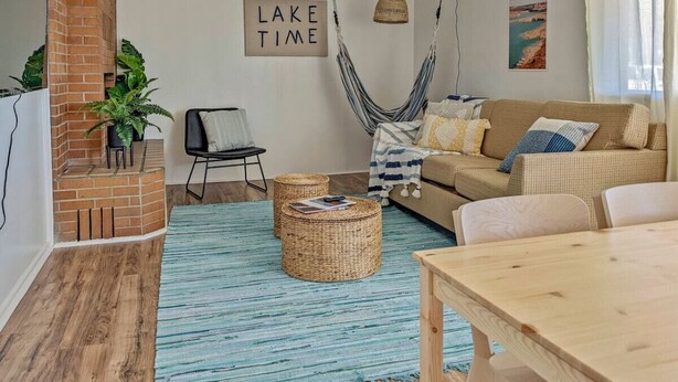 Ein gemütliches Wohnzimmer mit einer Hängematte, einer Couch, einem Holztisch und einem Kamin aus Backsteinen.