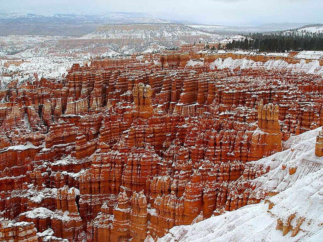 Vasta paisagem de cânion com formações rochosas cobertas de neve.
