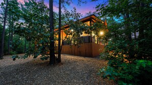 A modern wooden cabin with a gravel driveway surrounded by trees. - Campfire Dreams: Arcade, Hot Tub, Playset, 3BD/3Bath, Pet Friendly (Broken Bow)