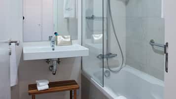 Un baño moderno con cabina de ducha de vidrio, tocador con espejo y bañera.