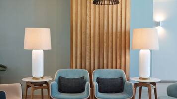A modern lounge area with two blue armchairs, a round coffee table, and two floor lamps.
