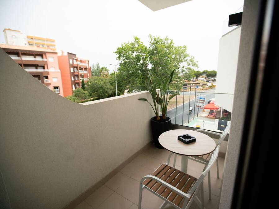 Ein Balkon mit einem Blumentopf, einem kleinen runden Tisch und einem Stuhl.