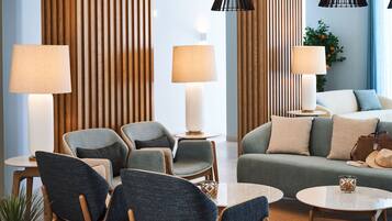 Un moderno vestíbulo de hotel con zonas de estar, lámparas y un sofá.