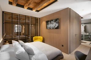 A modern bedroom with a large bed, a yellow armchair, and a wardrobe with sliding doors.