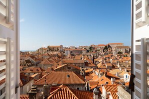 A panoramic view of a historic cityscape with terracotta-roofed buildings, a prominent church, and a clear blue sky.