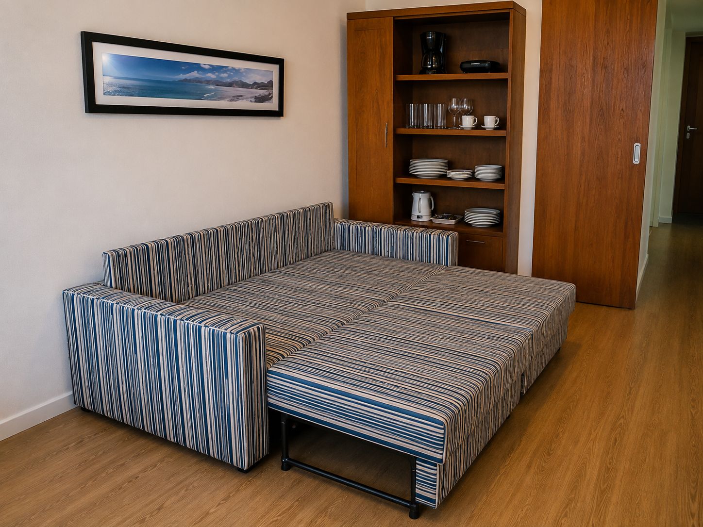 Ein gemütlicher Raum mit Schlafsofa, einem Holzschrank mit Geschirr und einem gerahmten Bild an der Wand.