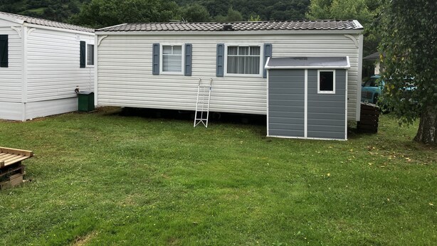 A mobile home with a small attached garage, a ladder, and a grassy yard. - Mobil Home Gère Belesten (Gère-Bélesten)