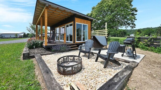 A modern outdoor patio with a fire pit, seating, and a grill.