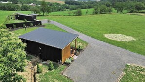 A rural property with a large barn, a gravel driveway, and expansive green fields.