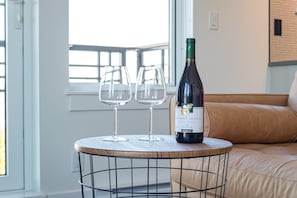 A round table with a wine bottle and two glasses on it, placed in a room with a window and a beige sofa. - Elegant Retreat in the Heart Old Town Victoria (Victoria)
