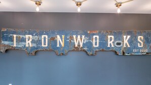 Een muur met de tekst 'IRONWORKS EST 2020' in een verweerde metalen stijl.