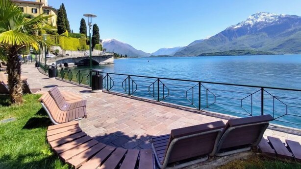 Une promenade au bord du lac, agrémentée de bancs et d’une rambarde, d’où l’on peut admirer un lac paisible et des montagnes.