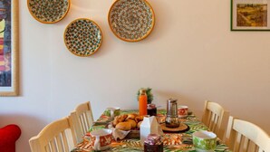 A dining area with a table set for four, surrounded by wooden chairs. There are three decorative plates on the wall above the table. - Apartment Bot by Interhome (Gravedona)