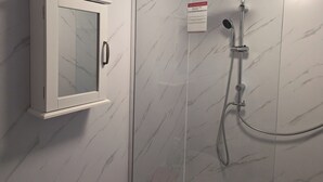 A bathroom with a shower, a medicine cabinet, and a clock.