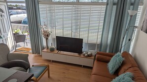 A modern living room with a sofa, TV, and a dining area.
