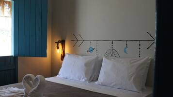 Ein Bett mit weißen Kissen und einem Handtuch, eine Wand mit einem Halbmond- und Sterndruck sowie ein Fenster mit blauen Rollläden.