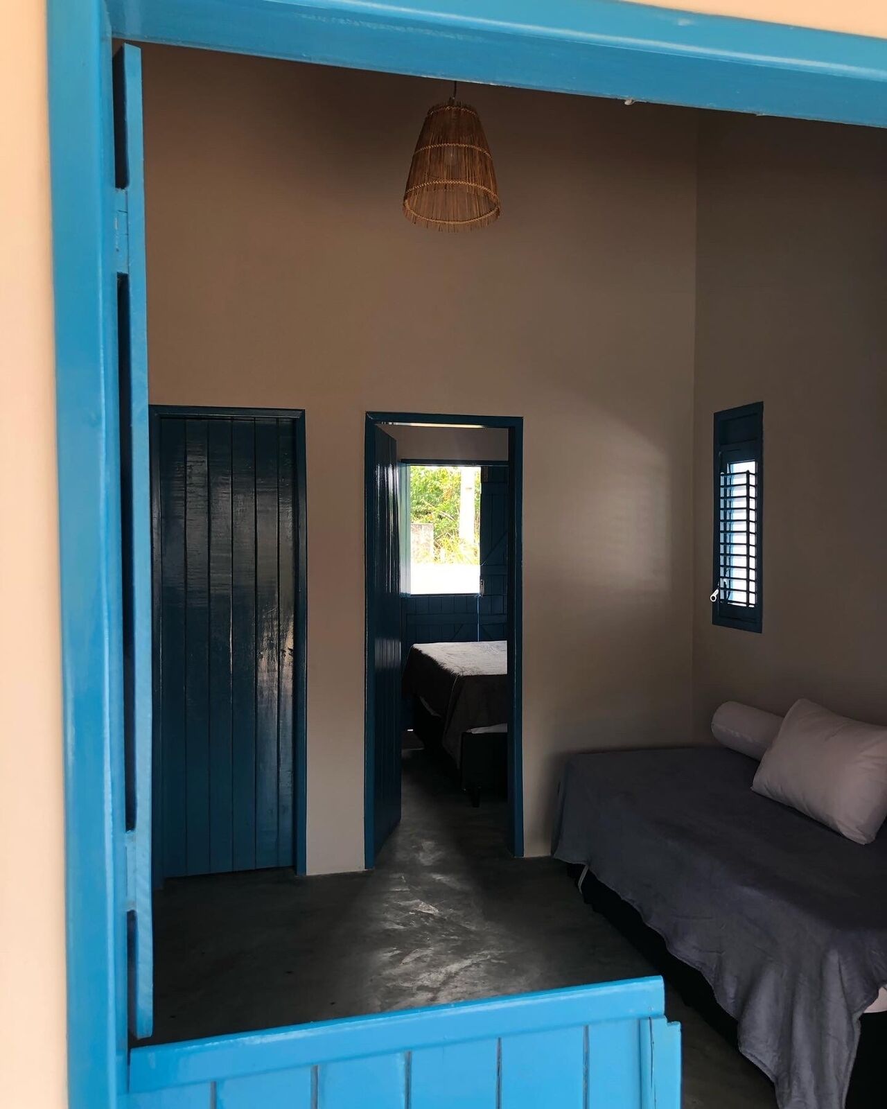 Quarto com uma cama, uma mesinha e um candeeiro suspenso.