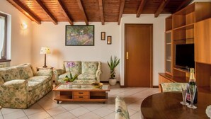 Una sala de estar con techo de madera, un sofá, una mesa de centro, un televisor y una estantería.