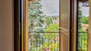Un balcón con vistas a un jardín y edificios.