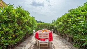 Une table dressée pour deux personnes, recouverte d’une nappe rouge, et entourée d’un luxuriant feuillage verdoyant.