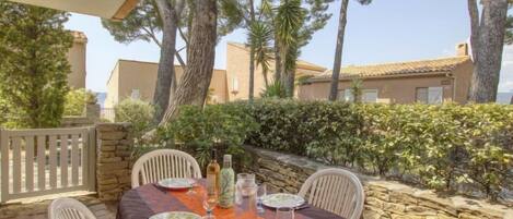 An outdoor dining area with a table set for four, surrounded by stone walls and trees.