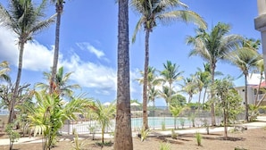 A landscaped area with palm trees, a pool, and a fenced pool area. - Hello Summer! beachfront studio in the heart of Orient Bay, pool direct access (Orient Bay)
