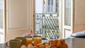Un safata d'esmorzar amb ous, rodanxes de taronja i croissants damunt d'una taula prop d'una finestra que dona a un balcó.