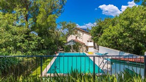 Piscina con vistas a una casa y follaje circundante.