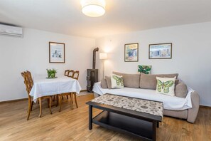 A living room with a dining table, wooden chairs, a sofa with patterned cushions, a coffee table, and a fireplace. - Holiday house DUNJA with private pool (Omišalj)