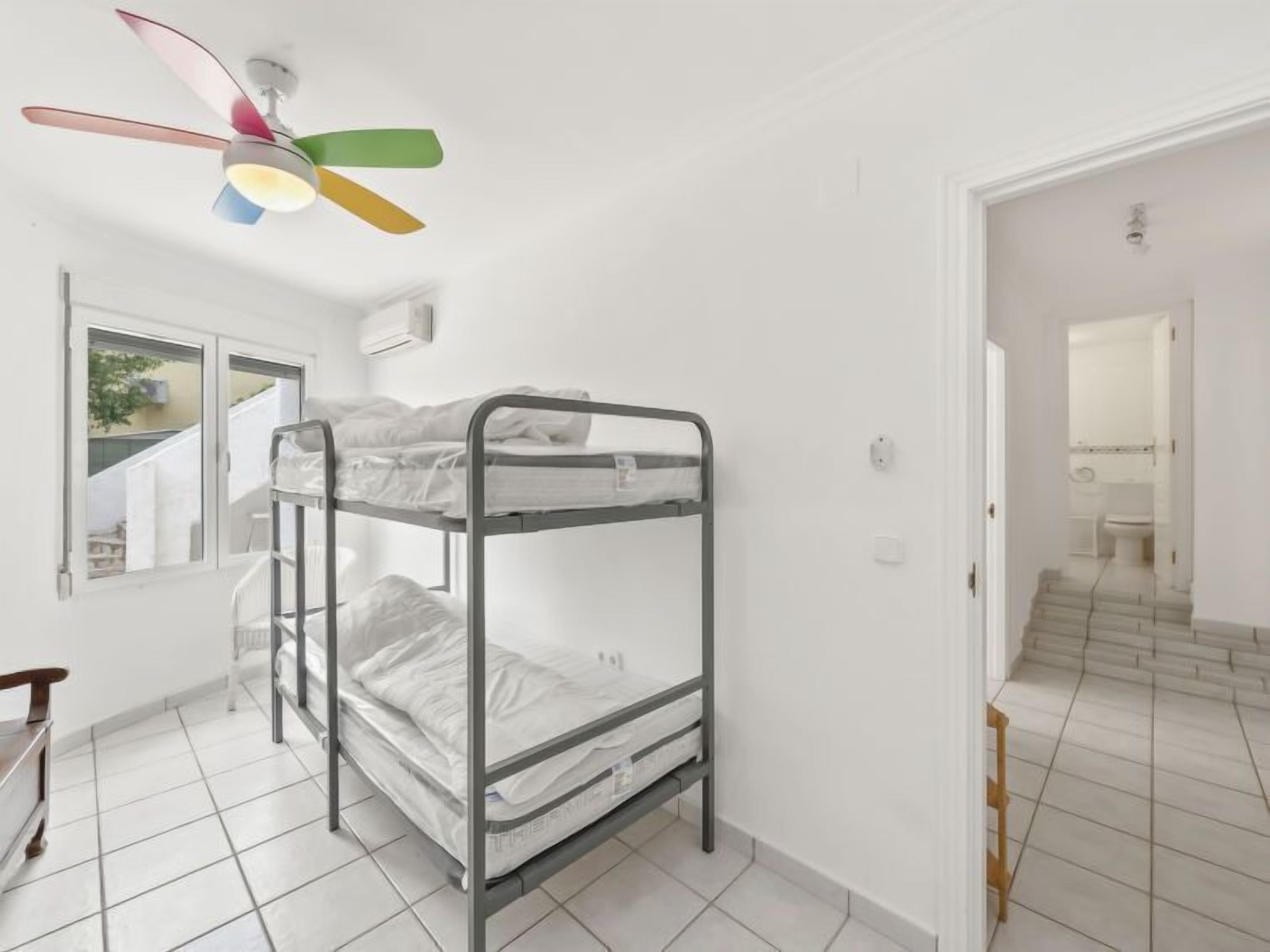 A bunk bed room with a ceiling fan, a window, and a view of the outside.